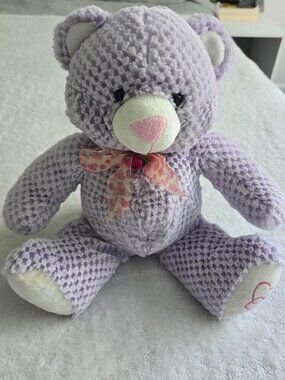 Purple knitted teddy bear with pink bow and heart